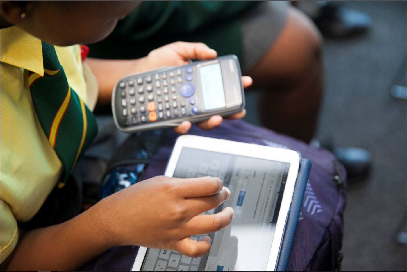 Student's hand using calculator and tab